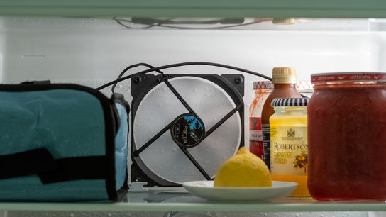 A regular computer fan is installed inside a refrigerator to circulate air inside it. The fan is placed at the back on the top shelf.