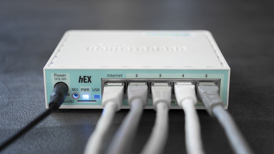 A small residential internet router with all its Ethernet sockets occupied by network cables.