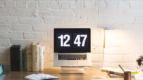 A MacBook laptop showing a full-screen digital clock.