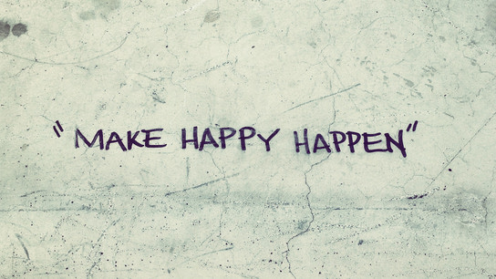 “Make Happy Happen” written on cracked and worn concrete.