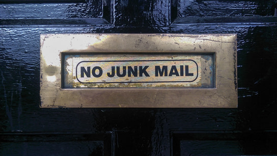 A door mail slot lableled “No Junk Mail”.