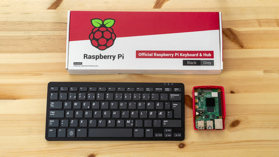 A Raspberry Pi 4 micro-computer next to a compact keyboard and its box boldly displaying the Raspberry Pi logo.