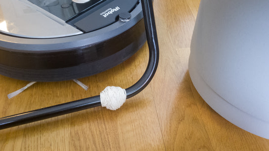 Twine wrapped around the bottom leg tubing of a laundry rack; raising it high enough off the floor to trigger a robot vacuum’s collision sensor.