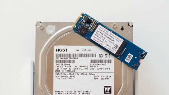 An M.2/NVMe disk laying on top of a hard disk drive.