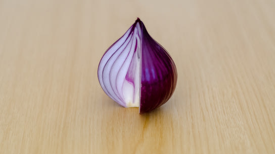 A red onion cut in the shape of the Tor Project logo.